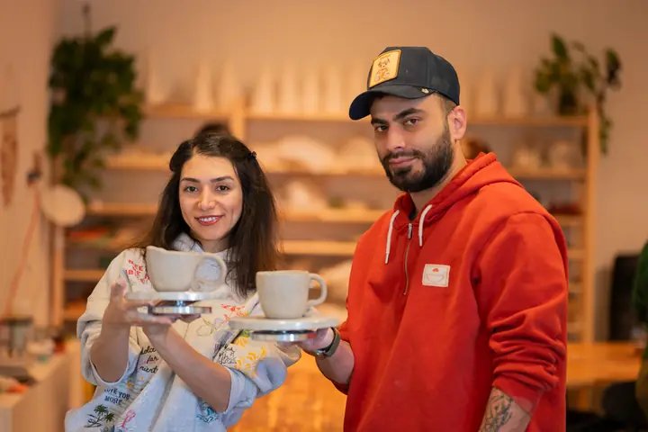 Two students holding up the mugs they made