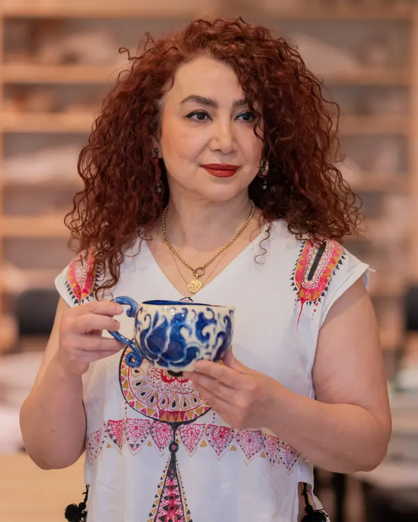 Marjan Hassaneini, ceramic artist and founder of Lemarsis Pottery Studio, holding a blue and white cup