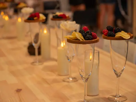 The long studio table set with candles, fruit and glasses