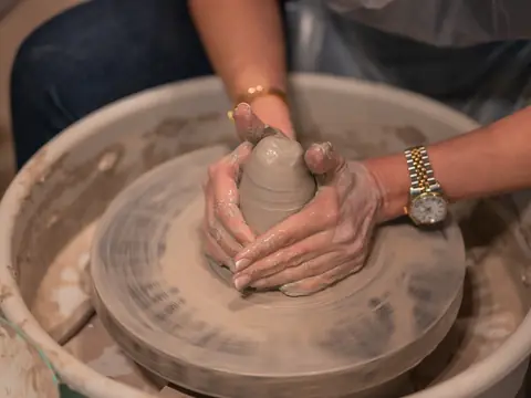 Hands coning clay up on the wheel