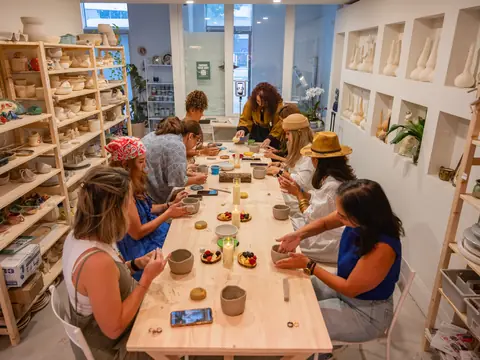A full table of students hand-building in the bright studio