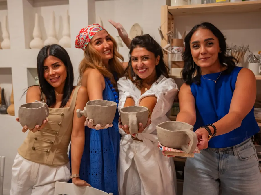 Four students holding up the cups they just made at the studio