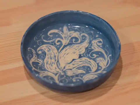 A blue bowl with a carved white floral design