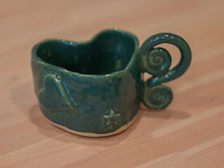 A heart-shaped green mug with a spiral handle