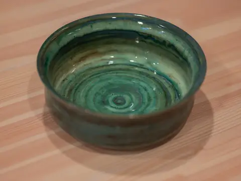 A deep green bowl with throwing rings inside