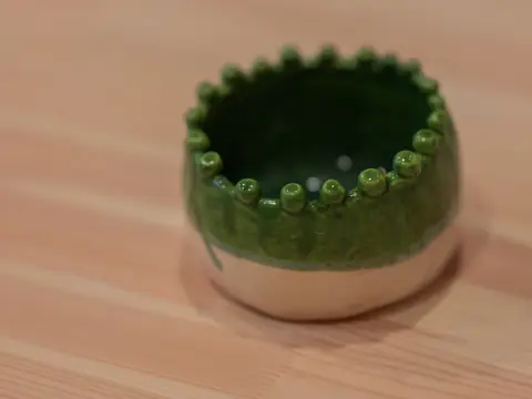 A small green and white pot with a beaded rim