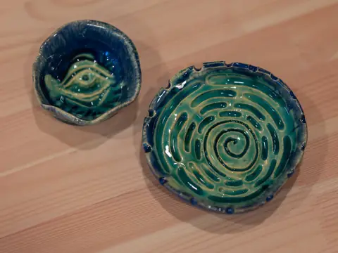 Two small dishes with carved spiral and eye patterns