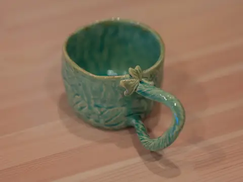 A textured turquoise mug with a twisted handle