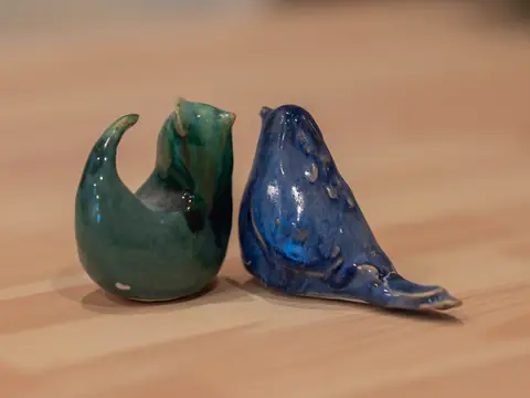 Two glazed clay birds, one green and one blue