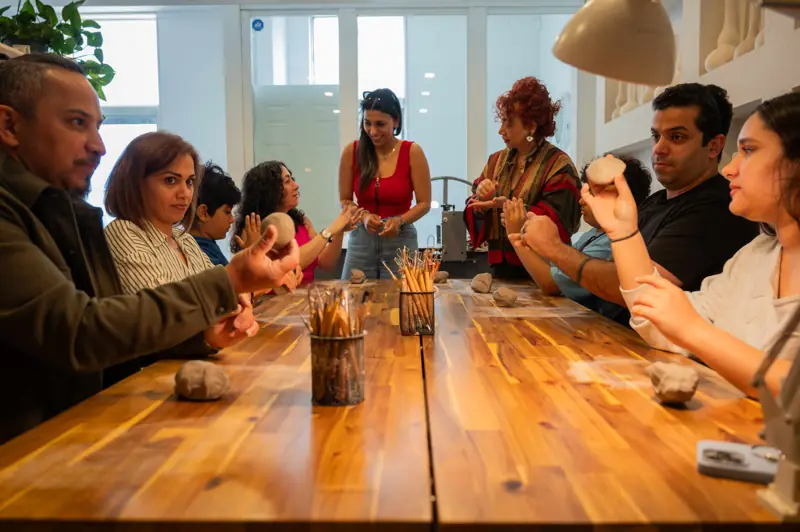 Marjan guiding students through pottery techniques in an intimate workshop setting.