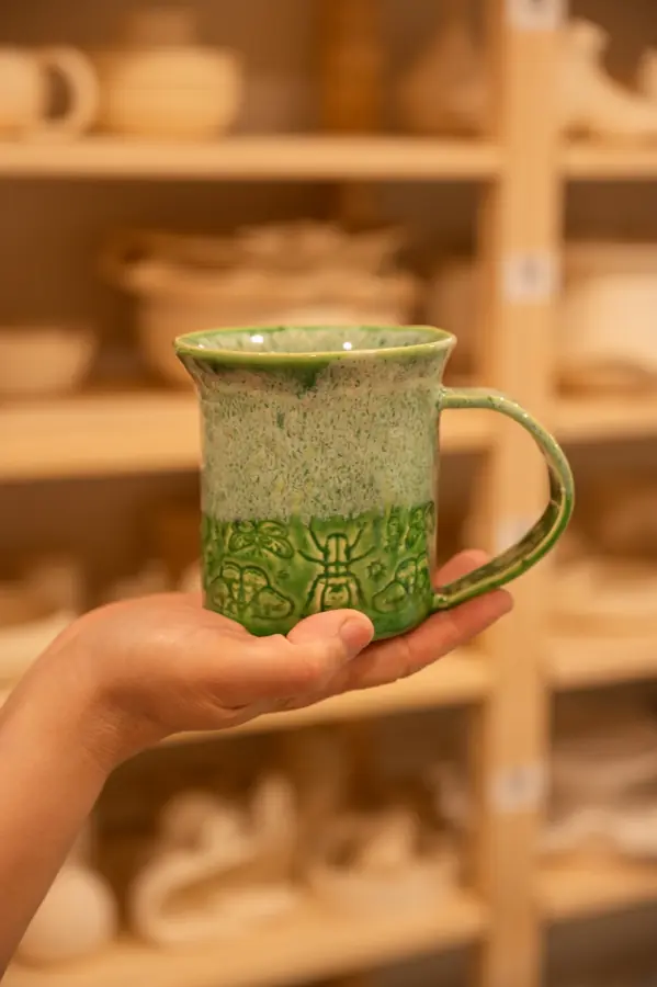 A hand-carved botanical mug made at the studio